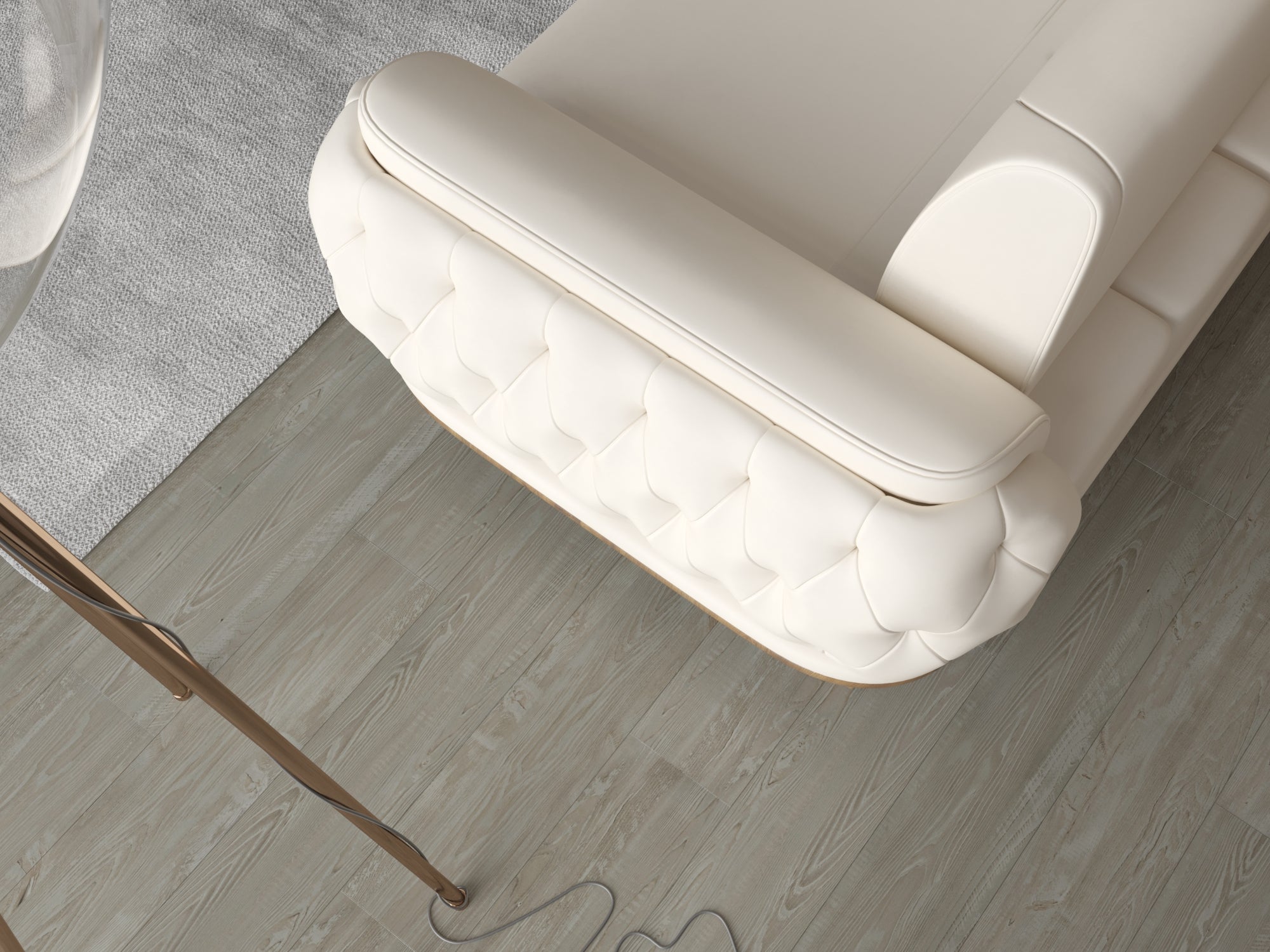 Draufsicht auf die Armlehne eines cremefarbenen Sofas mit gesteppter Polsterung und sichtbaren Ziernähten auf hellem Holzboden.
