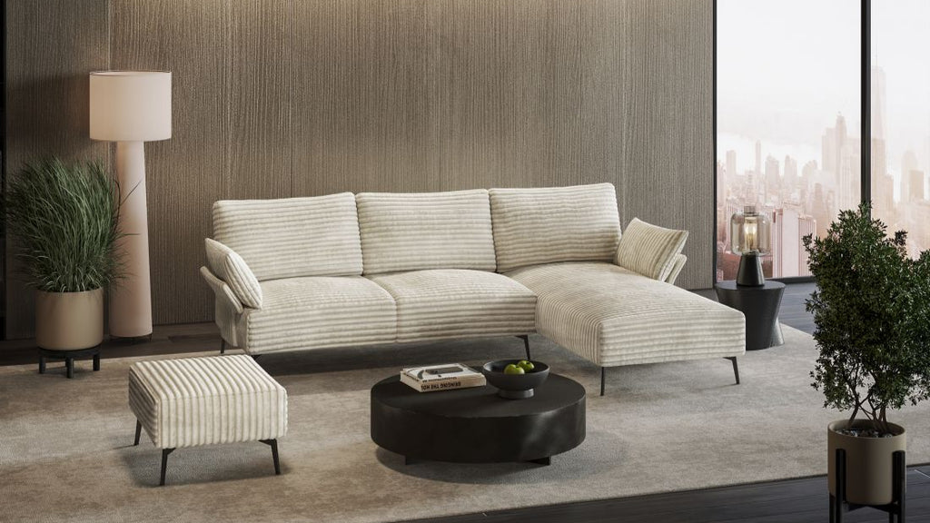 Helles gestreiftes Ecksofa mit Hocker und rundem Couchtisch vor großer Fensterfront mit Stadtblick.