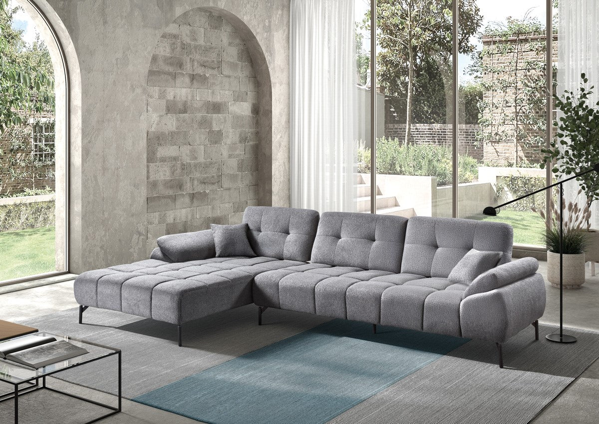 Graues Ecksofa mit Steppung und Ottomane in modernem Wohnbereich mit bodentiefen Fenstern.