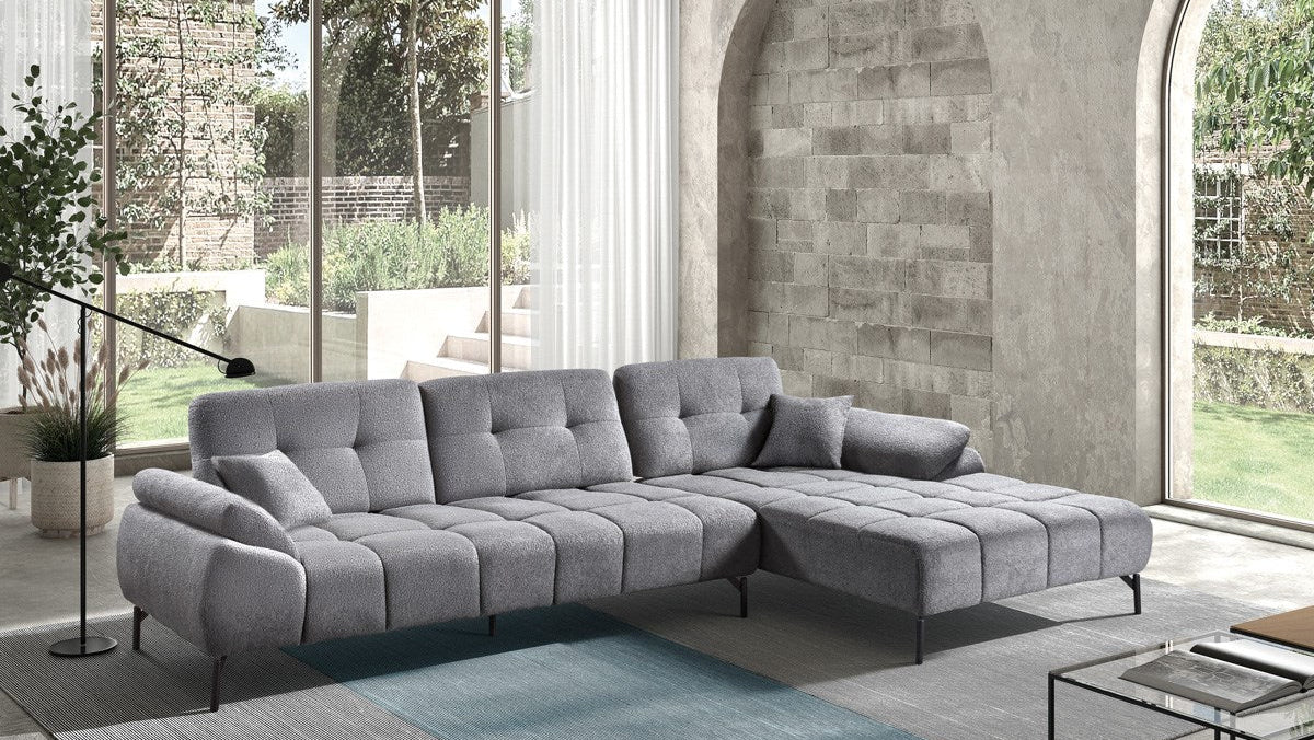 Graues Ecksofa mit Steppung und Recamiere in modernem Wohnraum mit großen Fensterflächen.