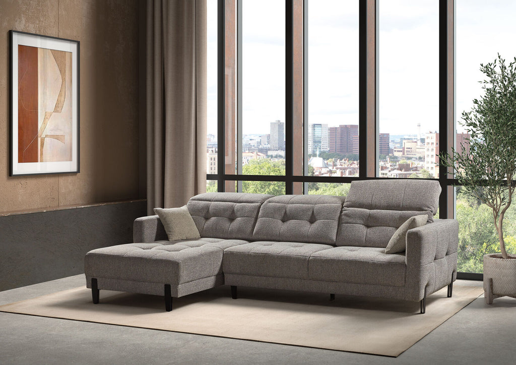 Modernes graues Ecksofa mit verstellbarer Kopfstütze vor großen Fenstern.