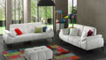 Helles Wohnzimmer mit zwei weißen Sofas, bunten Kissen und Patchwork-Teppich