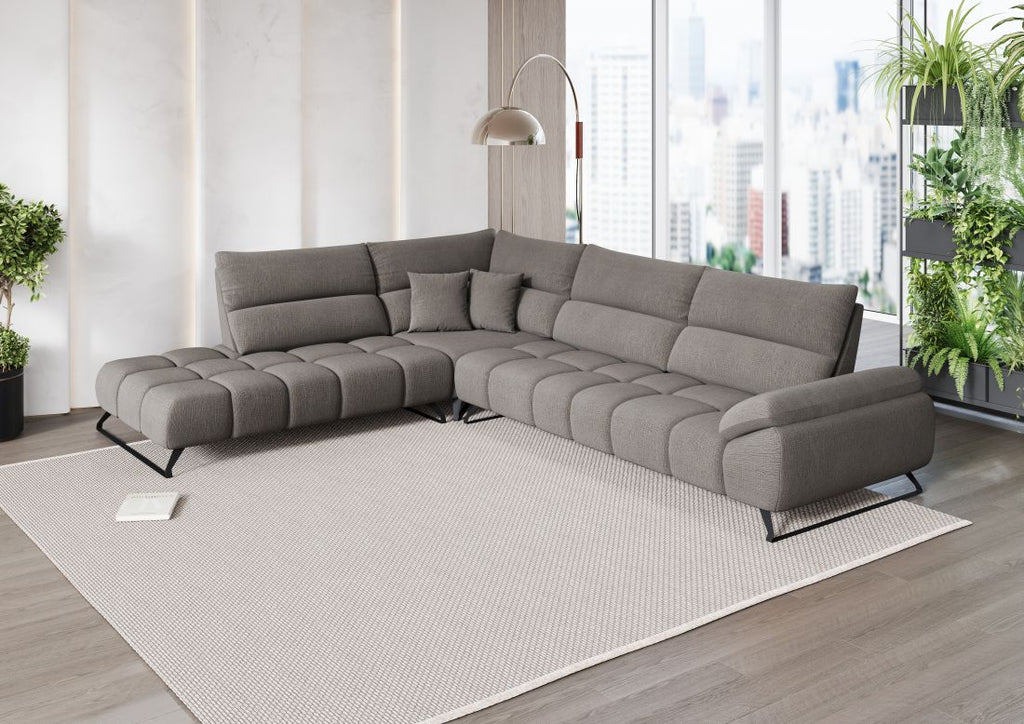 Modernes hellgraues Ecksofa mit Steppung in offenem Wohnraum mit großen Fenstern und Pflanzen.