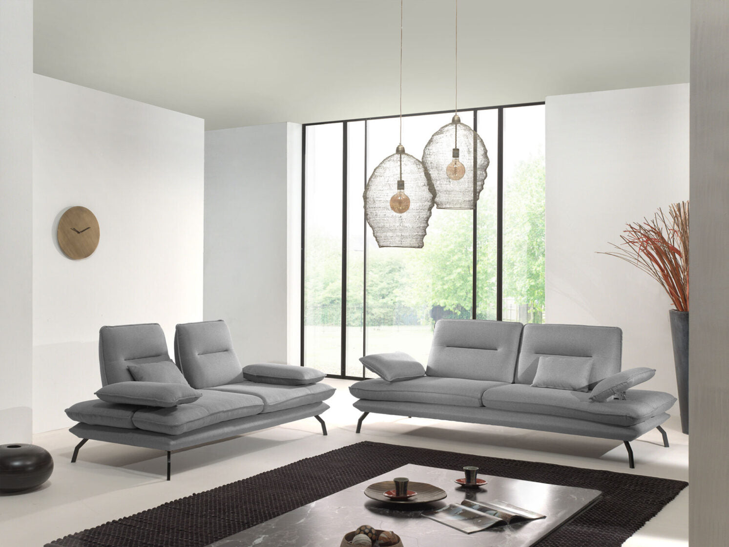 Modernes graues Sofa Set mit verstellbaren Armlehnen in hellem Wohnzimmer mit großen Fenstern
