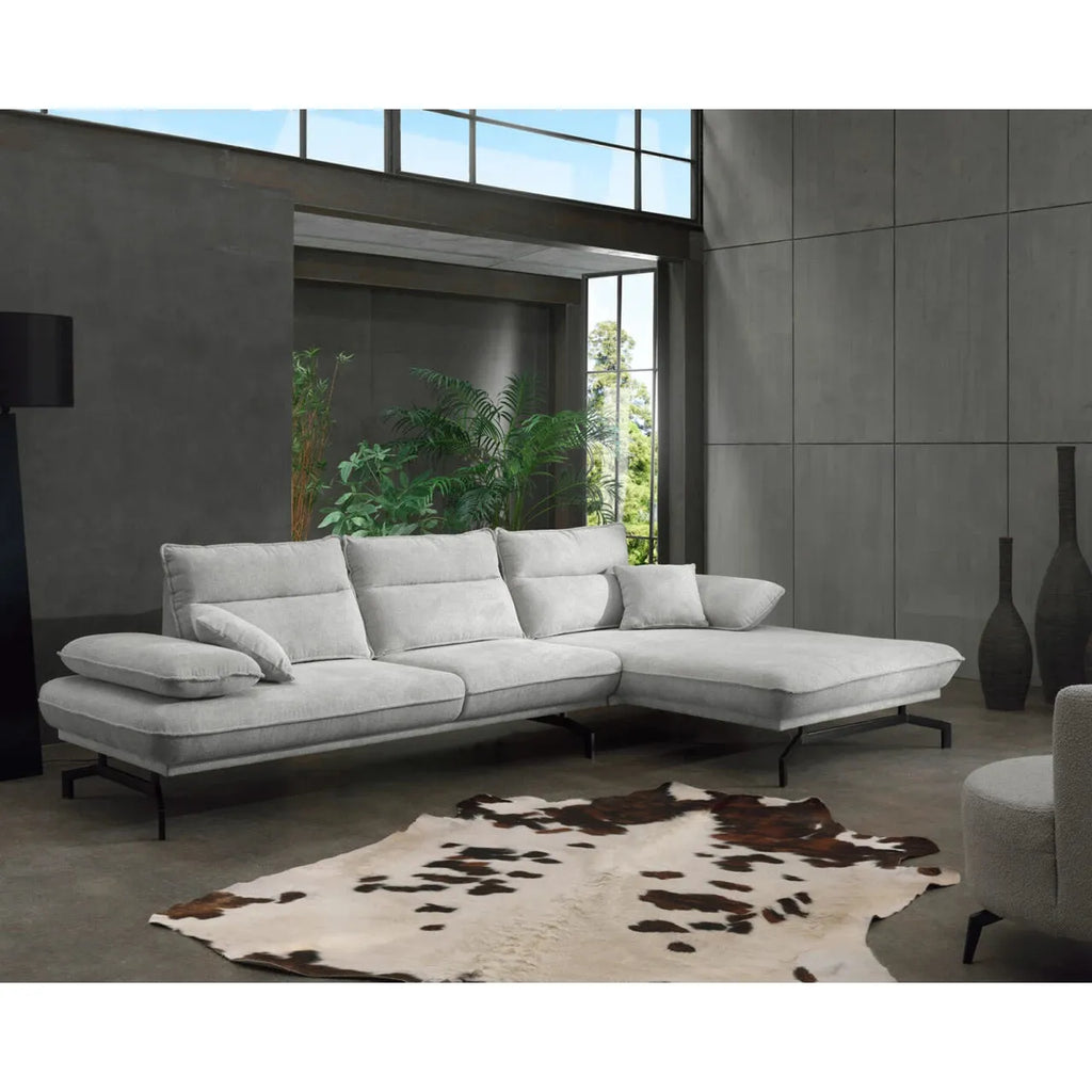 Modernes hellgraues Ecksofa mit Kissen in stilvollem Wohnraum mit Pflanzen und Kuhfell
