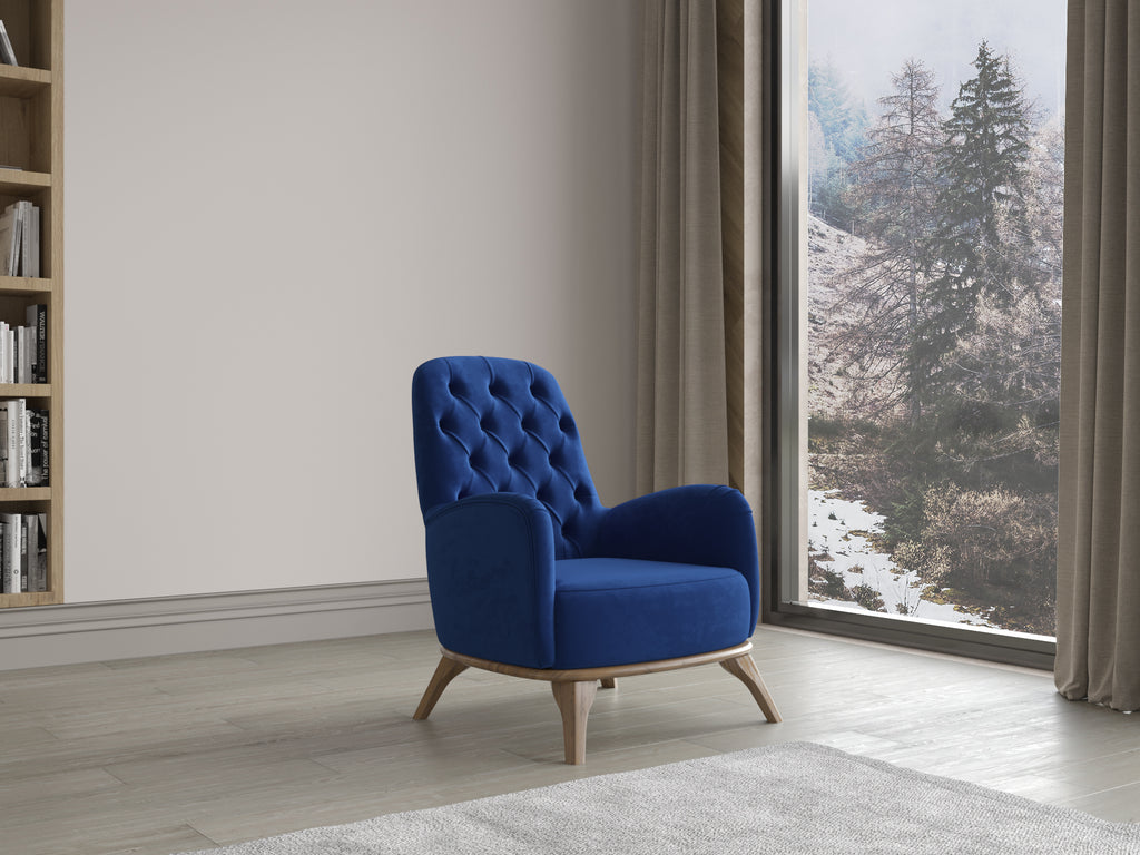 Blauer Polstersessel mit Knopfheftung und Holzfüßen vor großer Fensterfront mit Blick auf winterliche Landschaft.