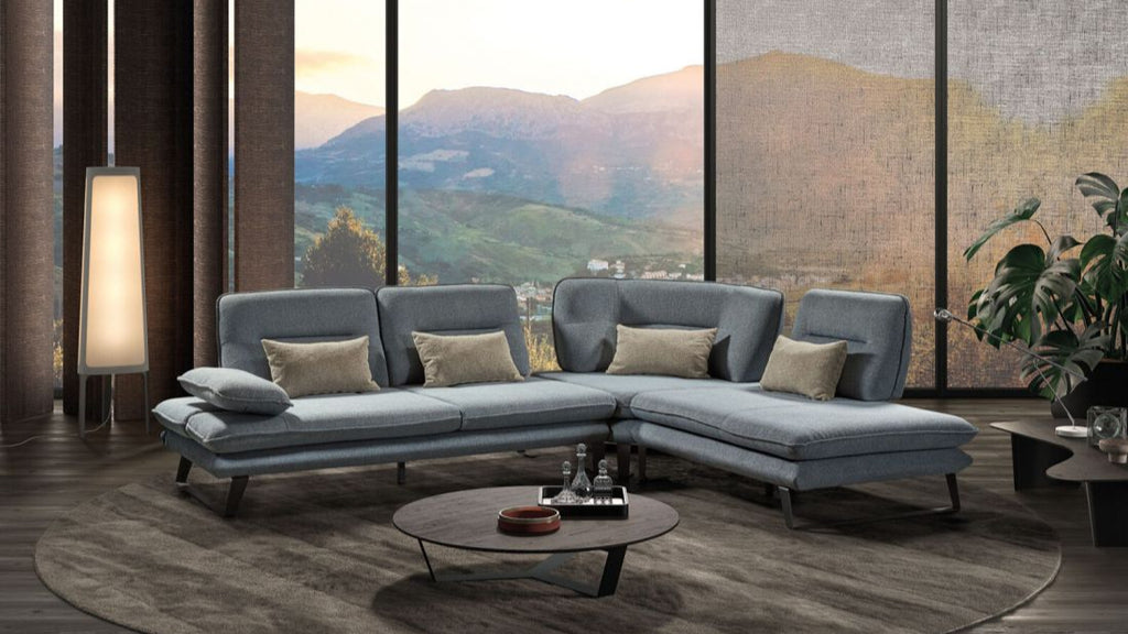 Moderne Wohnlandschaft in Grau mit Sofa vor bodentiefen Fenstern und Bergpanorama im Hintergrund.